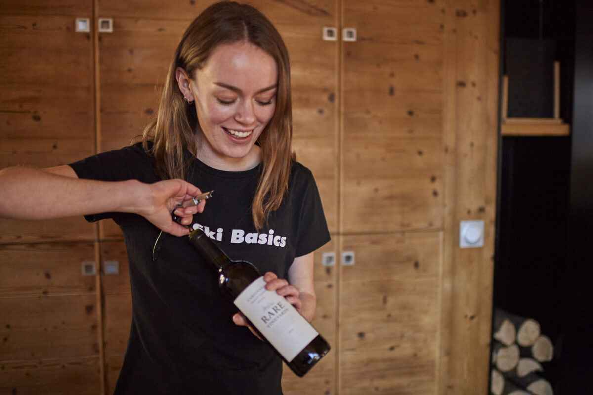 A Ski Basics chalet host opening a bottle of wine for guest in catered ski chalet in Meribel Village