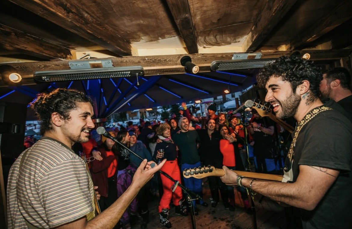 Apres ski in meribel. Image taken from behind a band playing on stage. Can see band members and people watching 