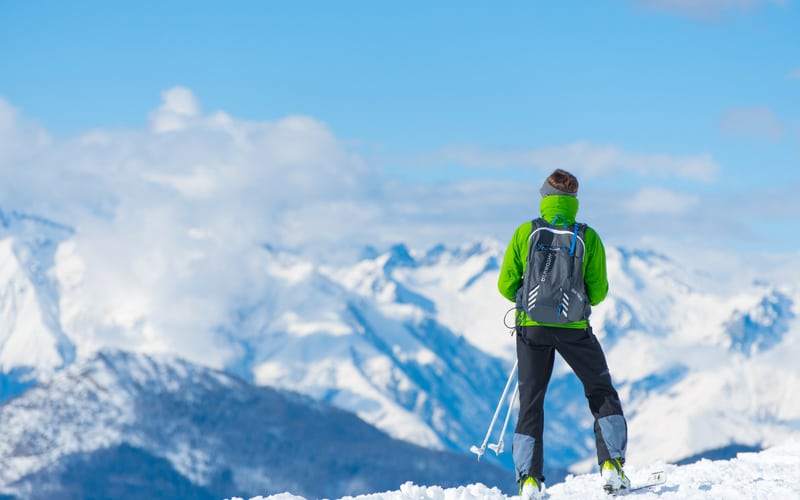 Person stood at top of a mountain in ski gear, looking out at the view
